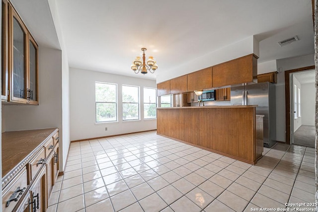 1 Carolyn Ln, Boerne, TX 78006 - kitchen with brown cabinetry, appliances with stainless steel finishes, a chandelier, light tile patterned floors, and glass insert cabinets