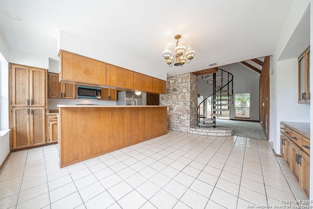 1 Carolyn Ln, Boerne, TX 78006 - kitchen with stainless steel appliances, a chandelier, brown cabinetry, light tile patterned flooring, and light countertops