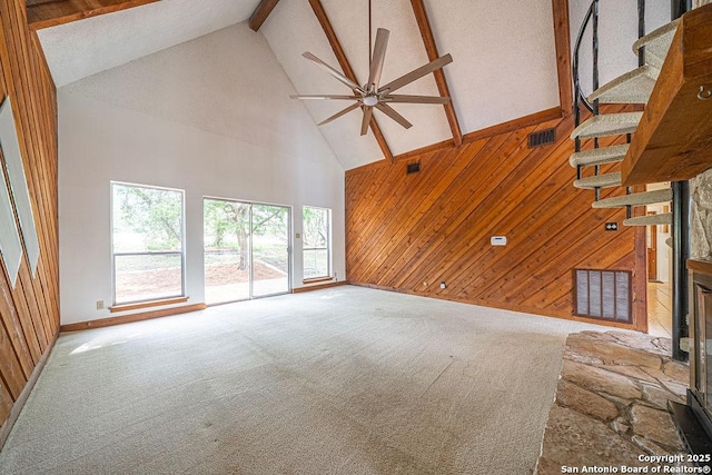 1 Carolyn Ln, Boerne, TX 78006 - unfurnished living room featuring high vaulted ceiling, wood walls, stairs, beam ceiling, and carpet