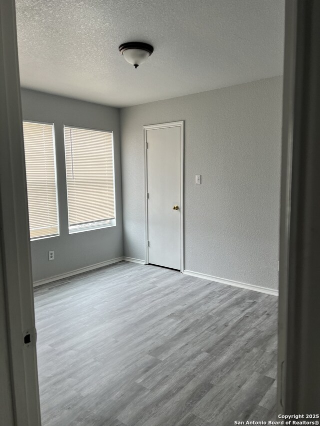 8619 Key N, Converse, TX 78109 - empty room featuring a textured ceiling, wood finished floors, baseboards, and a textured wall