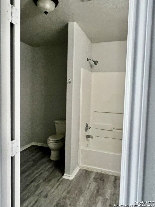 8619 Key N, Converse, TX 78109 - bathroom featuring toilet, baseboards, wood finished floors, and tub / shower combination