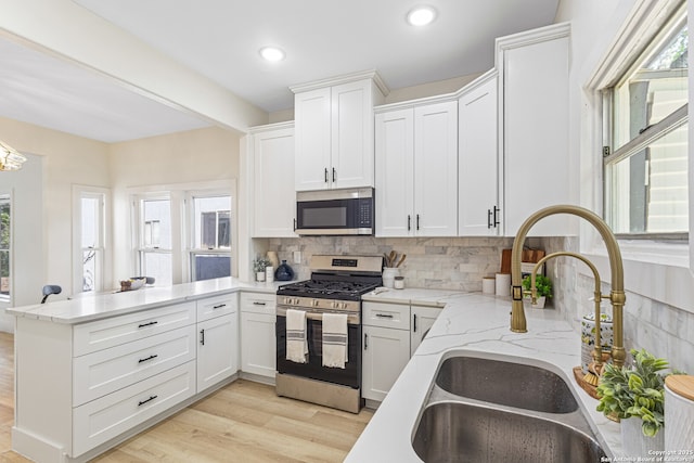 705 E Woodlawn Ave, San Antonio, TX 78212 - kitchen featuring appliances with stainless steel finishes, a sink, a peninsula, tasteful backsplash, and white cabinetry