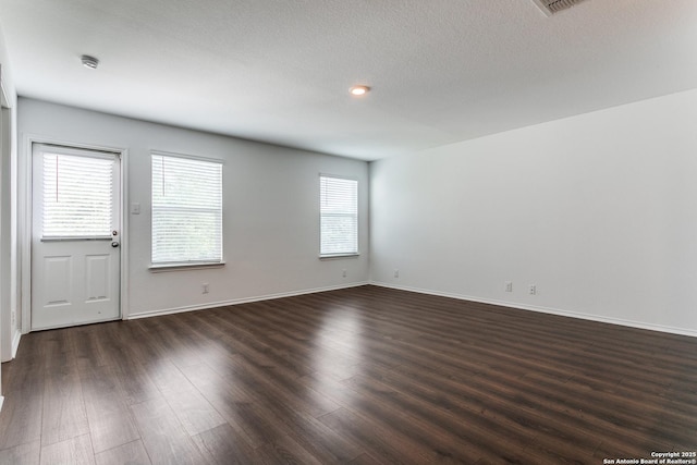 5518 Salado Fls, San Antonio, TX 78222 - empty room with dark wood-type flooring, baseboards, and a textured ceiling