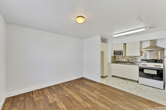 11219 Five Iron, San Antonio, TX 78221 - kitchen featuring white electric stove, wall chimney exhaust hood, tasteful backsplash, stainless steel microwave, and baseboards