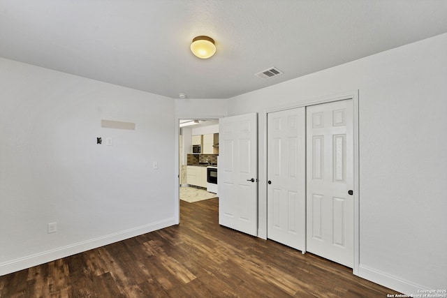 11219 Five Iron, San Antonio, TX 78221 - unfurnished bedroom with baseboards, dark wood-style flooring, and a closet