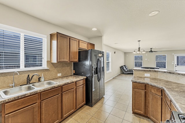 11219 Five Iron, San Antonio, TX 78221 - kitchen featuring black fridge with ice dispenser, a sink, a chandelier, decorative backsplash, and brown cabinets