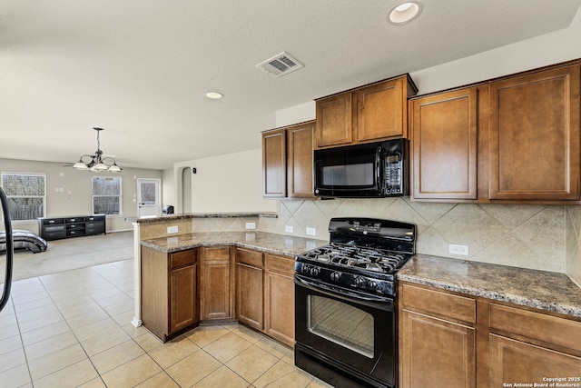 11219 Five Iron, San Antonio, TX 78221 - kitchen featuring black appliances, dark stone counters, a peninsula, light tile patterned floors, and a chandelier