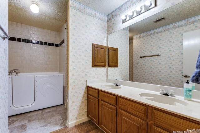 8763 Silent Oaks, San Antonio, TX 78250 - bathroom featuring a textured ceiling, a tub, double vanity, baseboards, and wallpapered walls