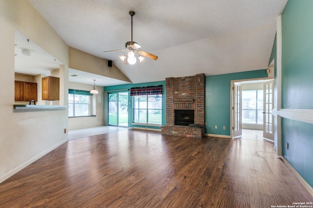 8763 Silent Oaks, San Antonio, TX 78250 - unfurnished living room with lofted ceiling, a ceiling fan, wood finished floors, a fireplace, and baseboards