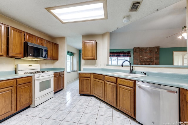 8763 Silent Oaks, San Antonio, TX 78250 - kitchen with black microwave, white range with gas cooktop, stainless steel dishwasher, a sink, and brown cabinets