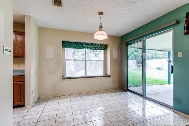 8763 Silent Oaks, San Antonio, TX 78250 - unfurnished dining area with a textured ceiling and light tile patterned flooring