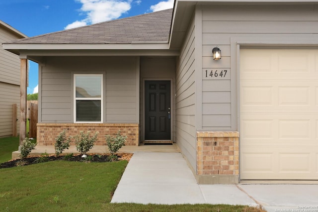 14647 Stirrup Trce, Elmendorf, TX 78112 - property entrance featuring brick siding, an attached garage, roof with shingles, and a lawn