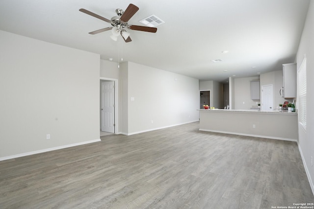 14647 Stirrup Trce, Elmendorf, TX 78112 - unfurnished living room with a ceiling fan, light wood finished floors, and baseboards