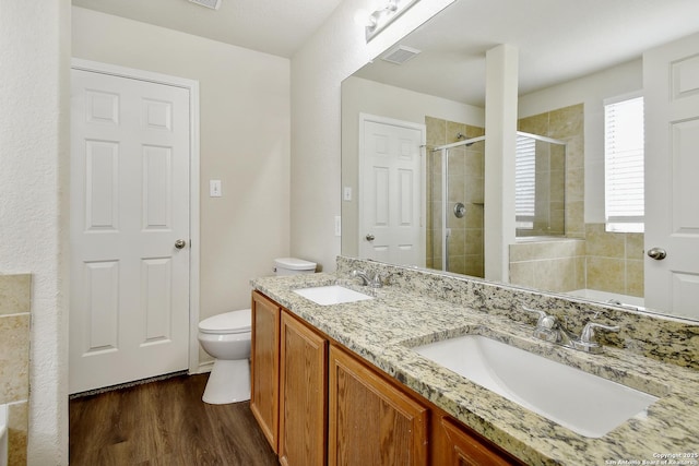 10374 Oakwood Crst, San Antonio, TX 78245 - bathroom featuring a shower stall, wood finished floors, double vanity, and toilet