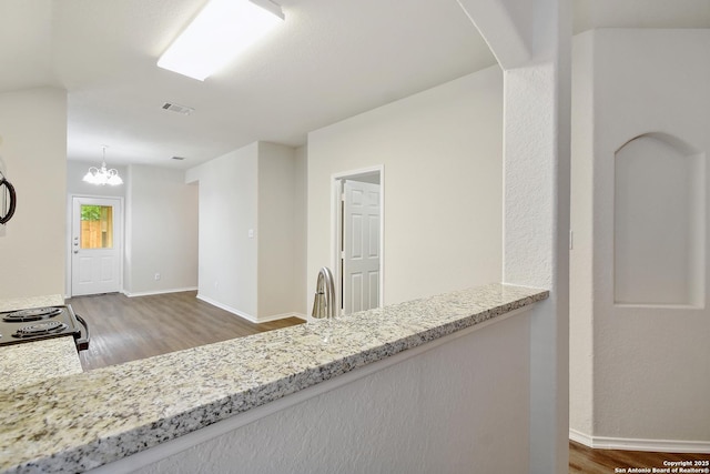 10374 Oakwood Crst, San Antonio, TX 78245 - kitchen featuring wood finished floors, arched walkways, light stone counters, and a chandelier