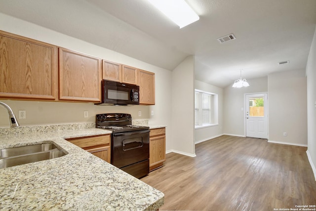 10374 Oakwood Crst, San Antonio, TX 78245 - kitchen with black appliances, a sink, lofted ceiling, light wood-style floors, and light stone countertops