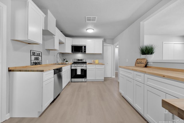 97 Denton, San Antonio, TX 78213 - kitchen with stainless steel appliances, butcher block countertops, a sink, and light wood-type flooring