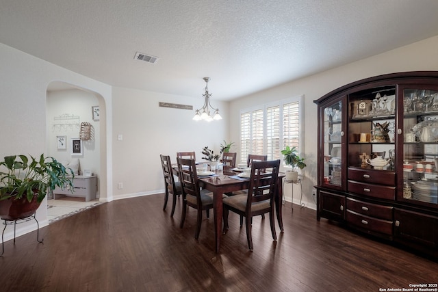 8022 Maddie Ln, San Antonio, TX 78255 - dining area featuring dark wood finished floors, arched walkways, a chandelier, baseboards, and a textured ceiling