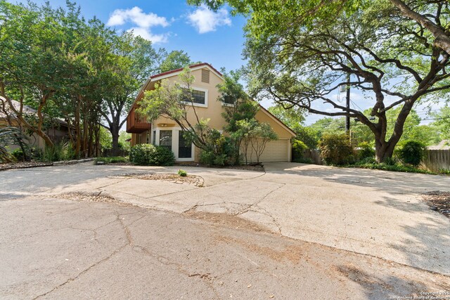 7519 Dijon Ct, San Antonio, TX 78209 - view of property hidden behind natural elements with concrete driveway, stucco siding, and an attached garage