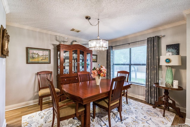 9618 Alderwood, San Antonio, TX 78250 - dining room featuring a chandelier, light wood finished floors, a textured ceiling, baseboards, and crown molding