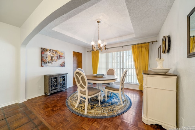 424 Fenwick Dr, Windcrest, TX 78239 - dining room featuring a raised ceiling, a textured ceiling, a chandelier, baseboards, and arched walkways