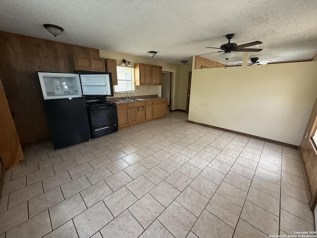 13338 Interstate 35, Moore, TX 78057 - kitchen with black electric range oven, a sink, a ceiling fan, a textured ceiling, and wooden walls