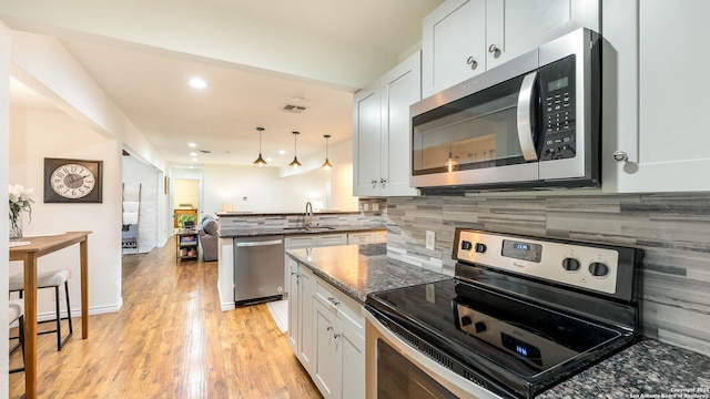 511 Serenade, San Antonio, TX 78216 - kitchen featuring appliances with stainless steel finishes, a sink, a peninsula, light wood-type flooring, and tasteful backsplash