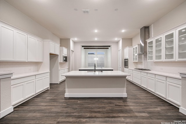 557 Poe Pkwy, Castroville, TX 78009 - kitchen with wall chimney range hood, a center island with sink, appliances with stainless steel finishes, a sink, and white cabinetry