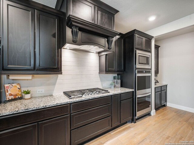 126 Stout Cv, Cibolo, TX 78108 - kitchen with appliances with stainless steel finishes, decorative backsplash, light wood-style floors, baseboards, and light stone countertops