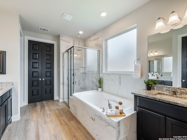 126 Stout Cv, Cibolo, TX 78108 - full bathroom featuring a shower stall, a garden tub, two vanities, wood finished floors, and baseboards