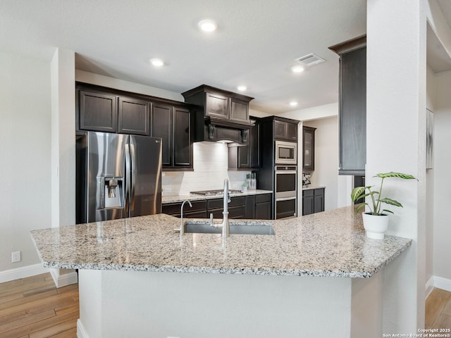 126 Stout Cv, Cibolo, TX 78108 - kitchen featuring appliances with stainless steel finishes, baseboards, light wood finished floors, light stone counters, and backsplash