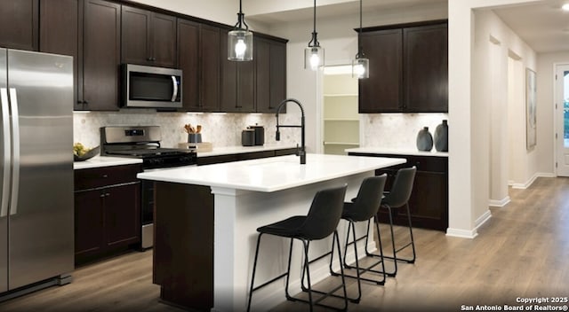231 Moose Trl, Cibolo, TX 78108 - kitchen with stainless steel appliances, wood finished floors, backsplash, a kitchen bar, and light countertops