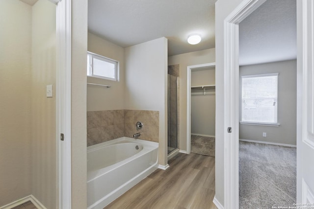 15206 Field Sparrow, San Antonio, TX 78253 - full bath with a garden tub, a shower stall, a walk in closet, wood finished floors, and baseboards