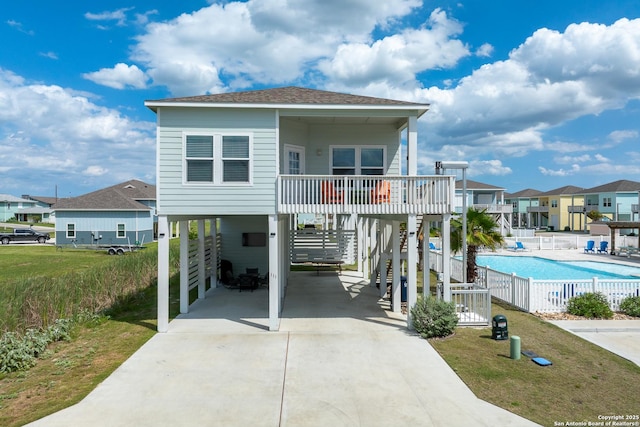 111 Great Chagos, Rockport, TX 78382 - view of front of property with a carport, concrete driveway, a community pool, a residential view, and roof with shingles