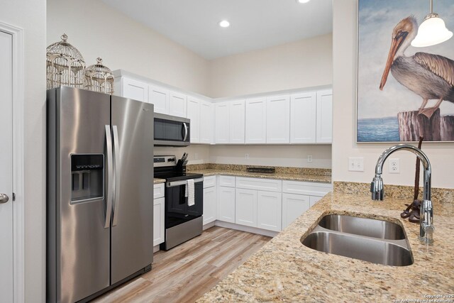 111 Great Chagos, Rockport, TX 78382 - kitchen with stainless steel appliances, a sink, white cabinetry, light wood-type flooring, and light stone countertops