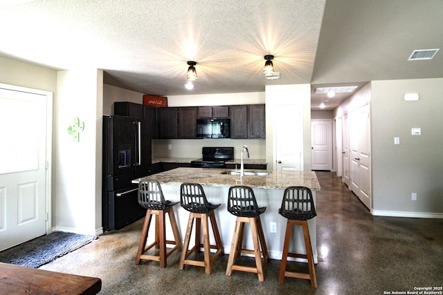 1349 Covered Wagon, Spring Branch, TX 78070 - kitchen featuring black appliances, a sink, baseboards, a kitchen bar, and a textured ceiling