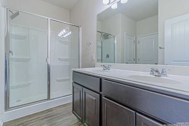 2733 Barkey Spg, San Antonio, TX 78245 - bathroom featuring a shower stall, wood finished floors, double vanity, and a textured wall
