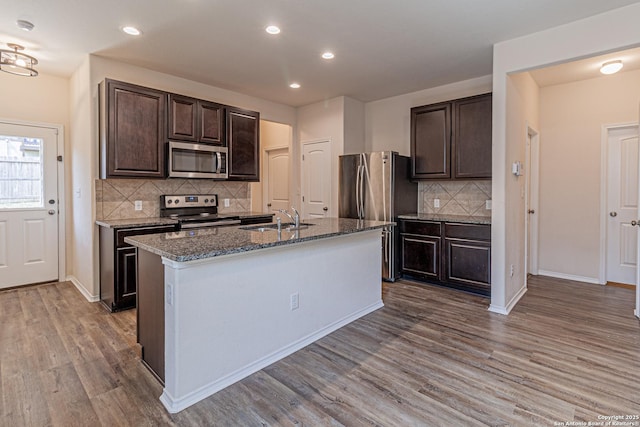 2733 Barkey Spg, San Antonio, TX 78245 - kitchen featuring appliances with stainless steel finishes, a sink, wood finished floors, dark brown cabinetry, and backsplash
