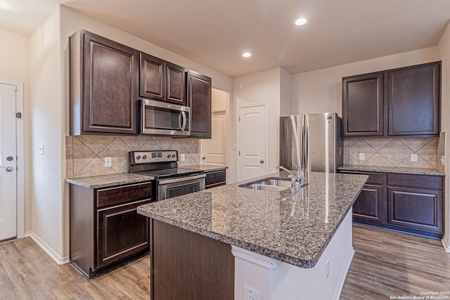 2733 Barkey Spg, San Antonio, TX 78245 - kitchen with stainless steel appliances, a sink, light wood-style floors, dark brown cabinets, and stone countertops