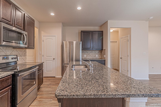2733 Barkey Spg, San Antonio, TX 78245 - kitchen featuring stainless steel appliances, a sink, light wood-type flooring, a center island with sink, and baseboards