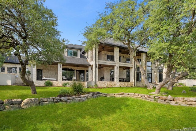 113 Carino Cv, Boerne, TX 78006 - rear view of house featuring stone siding, a balcony, a lawn, and roof with shingles