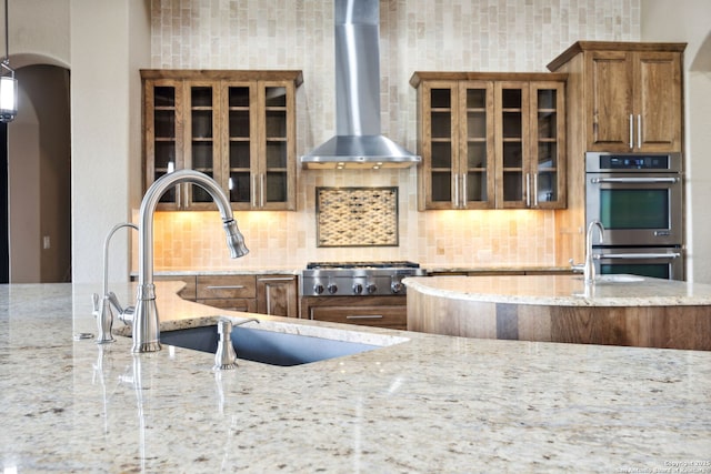 1078 Star Rdg, Spring Branch, TX 78070 - kitchen with wall chimney range hood, appliances with stainless steel finishes, a sink, light stone countertops, and brown cabinets