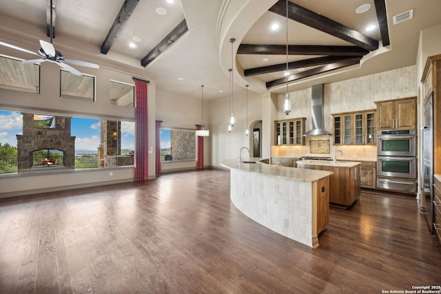 1078 Star Rdg, Spring Branch, TX 78070 - kitchen with a spacious island, wall chimney range hood, brown cabinets, a ceiling fan, and beam ceiling