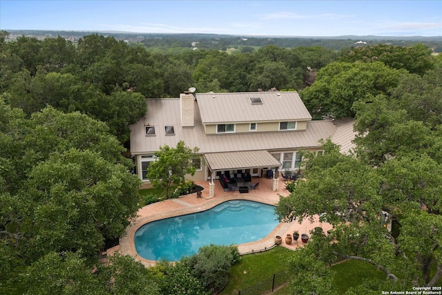 29729 Mellow Wind, Fair Oaks Ranch, TX 78015 - back of house with a chimney, a wooded view, a patio, an outdoor pool, and metal roof