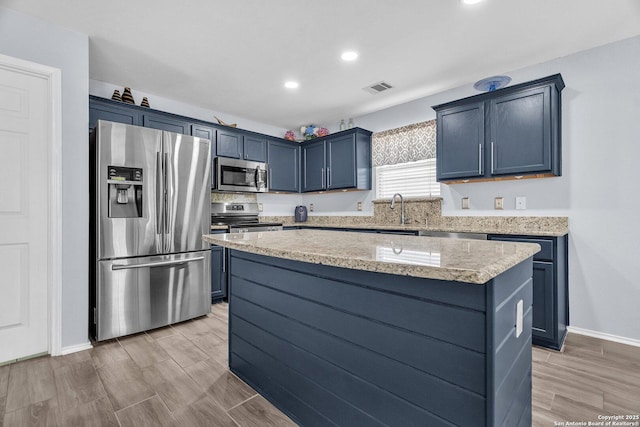 7715 Beechnut Oak, San Antonio, TX 78223 - kitchen featuring stainless steel appliances, a center island, a sink, blue cabinetry, and light stone countertops