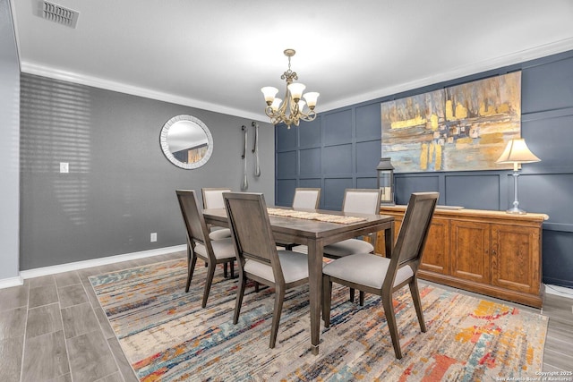 7715 Beechnut Oak, San Antonio, TX 78223 - dining area featuring a decorative wall, a chandelier, baseboards, ornamental molding, and light wood-type flooring