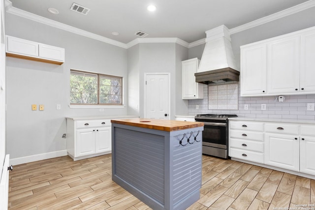 838 Georg Oaks, Bulverde, TX 78163 - kitchen with wood counters, stainless steel range with electric stovetop, custom range hood, light wood finished floors, and tasteful backsplash
