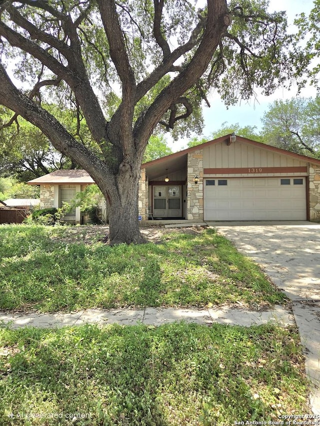 1319 Tideland, San Antonio, TX 78245 - view of front of house featuring stone siding, an attached garage, driveway, and board and batten siding