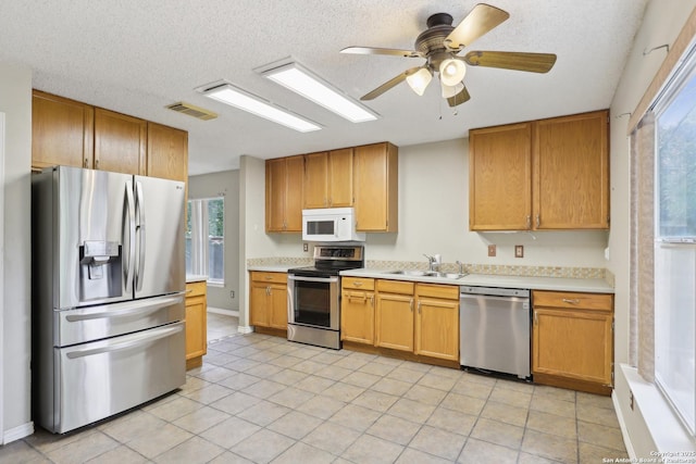 15527 Legend Spgs, San Antonio, TX 78247 - kitchen with appliances with stainless steel finishes, a sink, light countertops, healthy amount of natural light, and a textured ceiling