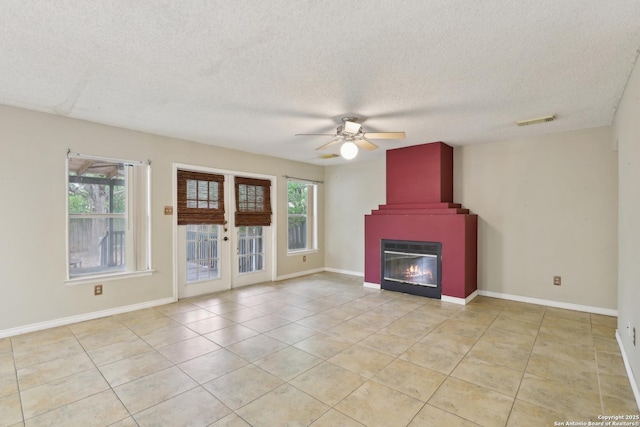15527 Legend Spgs, San Antonio, TX 78247 - unfurnished living room featuring ceiling fan, a textured ceiling, light tile patterned flooring, a large fireplace, and french doors